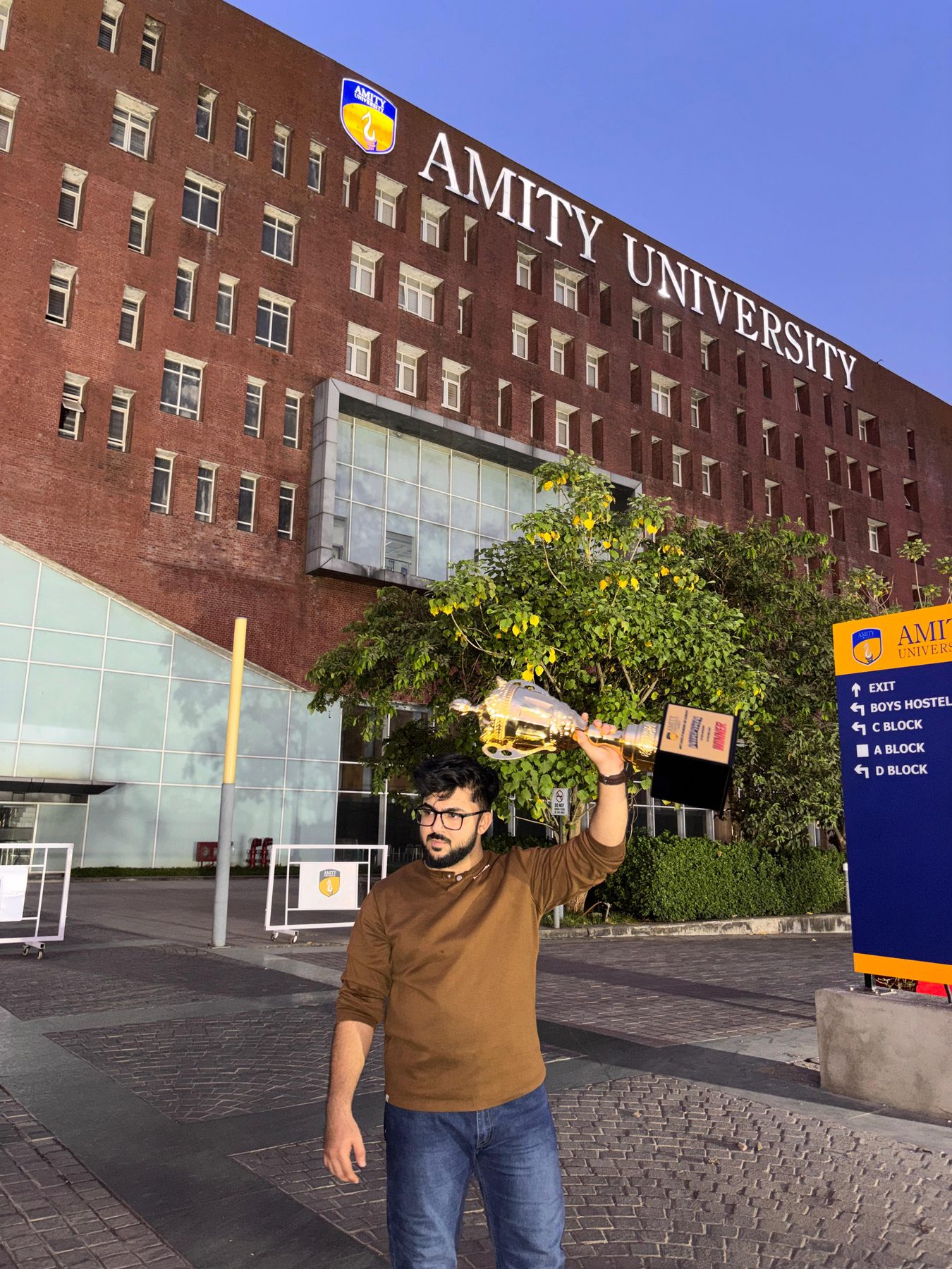 Saud Satopay holding the Nirman 2026 trophy outside the Amity University Mumbai building